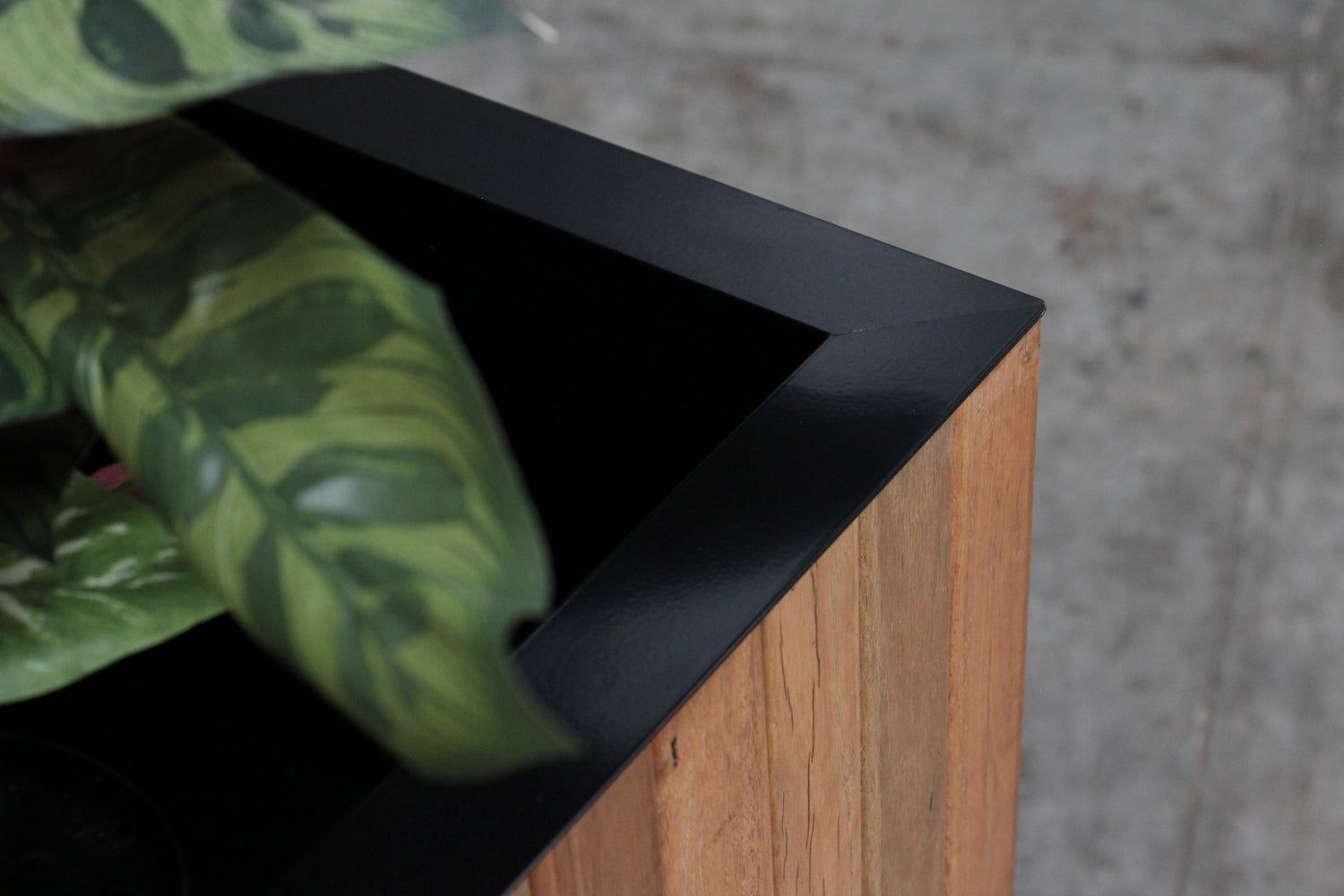Image of metal powder coated capping detail on a spotted gum planter box. Designed and fabricated for a commercial developer in Queensland and sent to an aged care facility. The clients specified requirements and we made the planters to suit. 